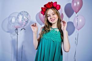 Happy girl in green turqoise dress and wreath with colored balloons isolated on white. Celebrating birthday theme. photo