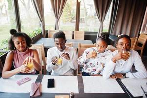 Happy african friends sitting and chatting in cafe. Group of black peoples meeting and drink juice in restaurant. photo