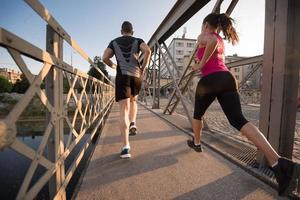 pareja joven corriendo por el puente en la ciudad foto
