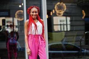 Fashionable african american girl at pink pants and red dreads posed outdoor. photo