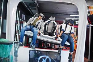 Two young indian people having fun with a new technology of a vr headset at virtual reality simulator. photo