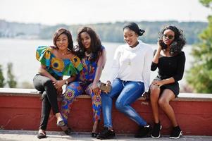 Group of four african american girls sitting outdoor and having fun. photo