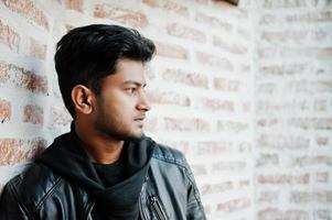 Smart young asian man wear on leather jacket posing against brick wall. photo