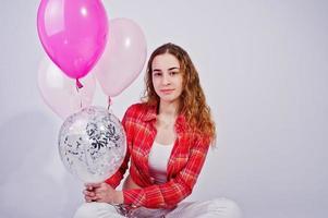 Young girl in red checked shirt and white pants with balloons against white background on studio. photo