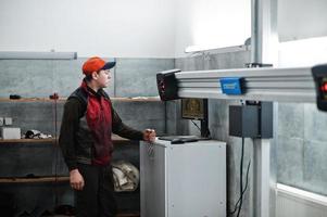 Auto mechanic sets american SUV car for diagnostics and configuration camber check in workshop of service station.. photo