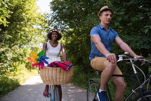 joven pareja multiétnica dando un paseo en bicicleta en la naturaleza foto