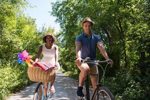 joven pareja multiétnica dando un paseo en bicicleta en la naturaleza foto