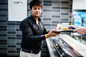 Waiter cashier gives order on food tray to stylish indian man. photo