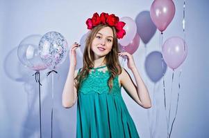 Happy girl in green turqoise dress and wreath with colored balloons isolated on white. Celebrating birthday theme. photo