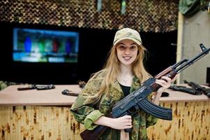 Girl with machine gun at hands on shooting range. photo