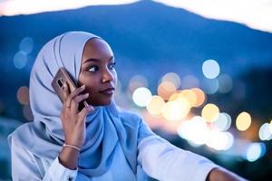 Young Muslim woman on  street at night using phone photo