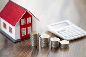 House and coins on table. Property investment and house mortgage financial concept, photo