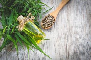 Seed hemp in a wooden spoon on the table, oil in a glass jar, CBD cannabis oil.Alternative herbs for medicine. copy space. photo