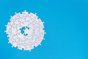 White jigsaw pieces on a blue background, Copy space, Jigsaw puzzle with missing piece. Completing final task. photo