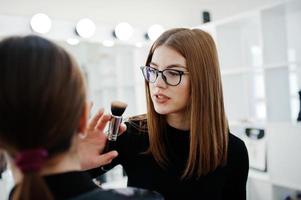 Make up artist work in her beauty visage studio salon. Woman applying by professional make up master. Beauty club concept. photo