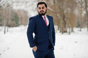 elegante hombre de negocios de barba india en traje posado en el día de invierno al aire libre. foto