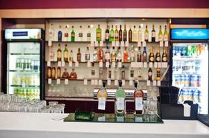 Multiple beer taps in a row against bar with bottles. photo