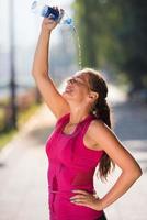 woman pouring water from bottle on her head photo