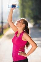 woman pouring water from bottle on her head photo