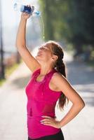 woman pouring water from bottle on her head photo