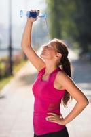 mujer echando agua de una botella en la cabeza foto