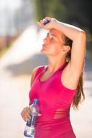 mujer bebiendo agua de una botella después de trotar foto