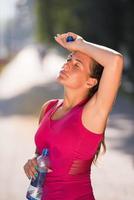 mujer bebiendo agua de una botella después de trotar foto