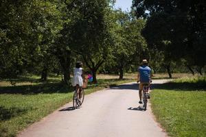 joven pareja multiétnica dando un paseo en bicicleta en la naturaleza foto