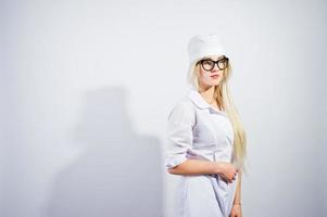Atractiva doctora o enfermera rubia con bata de laboratorio y gafas aisladas de fondo blanco. foto