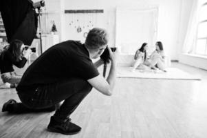 el equipo de dos fotógrafos fotografiando a las gemelas de estudio. fotógrafo profesional en el trabajo. foto