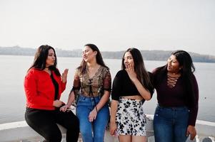 grupo de cuatro chicas latinas felices y bonitas de ecuador posaron contra el lado del lago. foto