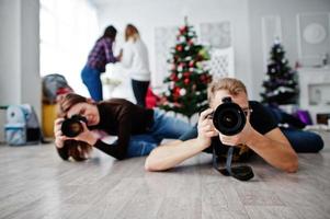 The team of two photographers lie on the floor and shooting on studio. photo