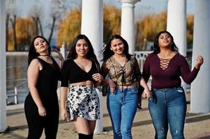 Group of four happy and pretty latino girls from Ecuador posed at street. photo