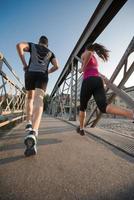 pareja joven corriendo por el puente en la ciudad foto
