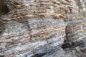 Layered rock on high steep sea bank photo