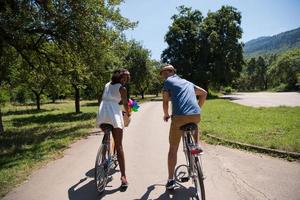 joven pareja multiétnica dando un paseo en bicicleta en la naturaleza foto