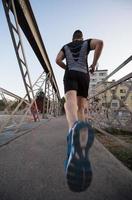 hombre corriendo por el puente en la mañana soleada foto