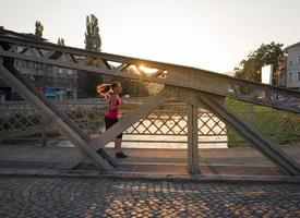 mujer corriendo por el puente en la mañana soleada foto