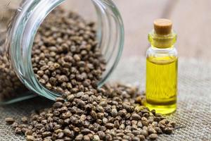 Hemp seeds and hemp oil on brown wooden table. CBD hemp oil. photo