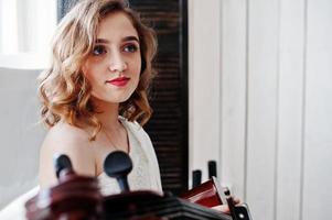 Pretty young gilrl musician in white dress with double bass. photo