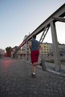 hombre corriendo por el puente en la mañana soleada foto