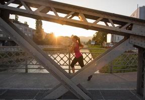 woman jogging across the bridge at sunny morning