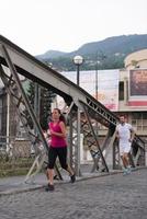 pareja joven corriendo por el puente en la ciudad foto