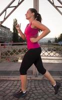 woman jogging across the bridge at sunny morning photo