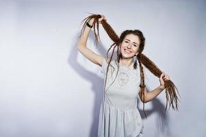 sesión de estudio de chica en vestido gris con rastas coletas sobre fondo blanco. foto