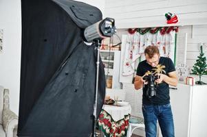 hombre fotógrafo mirando a la cámara para obtener el resultado de lo que dispara en el estudio. fotógrafo profesional en el trabajo. foto