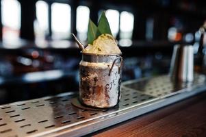 Alcoholic cocktail with ice in can glass on bar table. photo