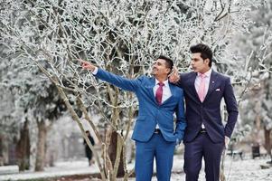 Two elegant indian fashionable mans model on suit posed at winter day, show something. photo