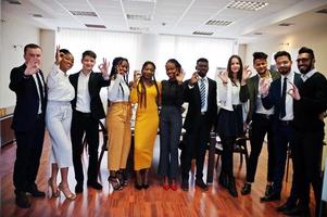 Large group of eleven multiracial business people standing at office and show ok sign together. Diverse group of employees in formal wear. photo