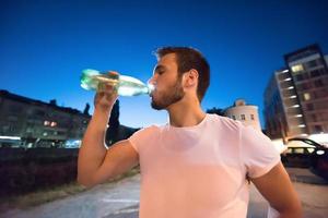 hombre bebiendo agua después de la sesión de carrera foto